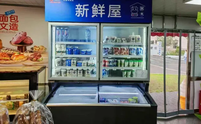 A combi freezer in a community supermarket displaying fresh milk in the upper chiller and ice cream in the lower frozen section.