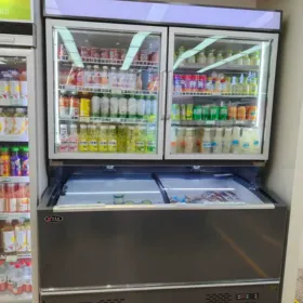 A space-saving combi freezer in a convenience store setting, displaying chilled drinks in the upper glass section and frozen food in the bottom chest.