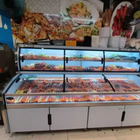 A ladder-style commercial cooler in a restaurant kitchen, organized with fresh meat skewers and ingredients for easy access.