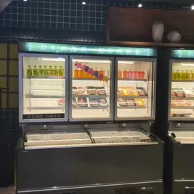 A space-saving combi freezer in a convenience store setting, displaying chilled drinks in the upper glass section and frozen food in the bottom chest.