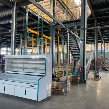Combination display cabinet inside a refrigeration workshop with steel framing and lifting equipment